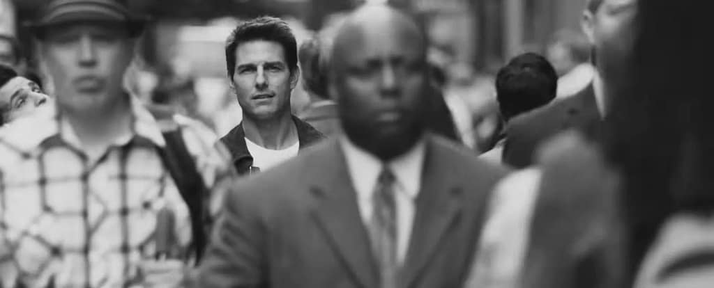 Black and white shot of Tom Cruise walking thoughtfully amidst a busy city crowd. Image credit: Oblivion (2013) - film still via Universal Pictures UK/YouTube.
