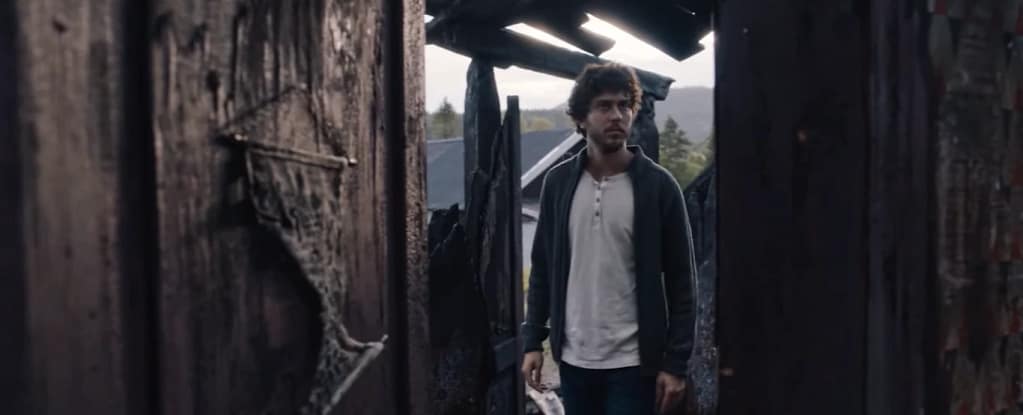 Nat Wolff as Eric walking through a burned house in Norway; screenshot via One Media.