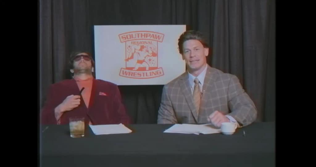 John Cena as studio host Lance Catamaran speaking to the camera while Fandango as Chett Chetterfield slumps back in his chair with sunglasses on.