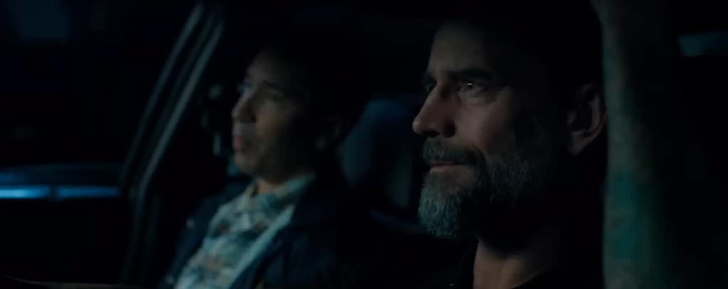 Deputy (Phil “CM Punk” Brooks) driving a police car alongside Ethan Hawkins (Justin Long) in Night Patrol. Image credit: Night Patrol film still - via Rotten Tomatoes Trailers/YouTube.
