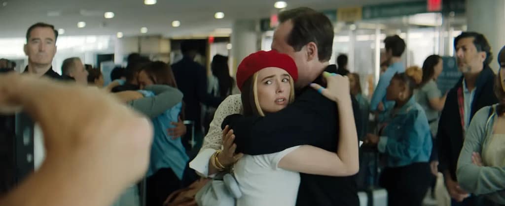 Zoey Deutch as Danni Sanders wearing a red beret and hugging her father at the airport in Not Okay (2022).