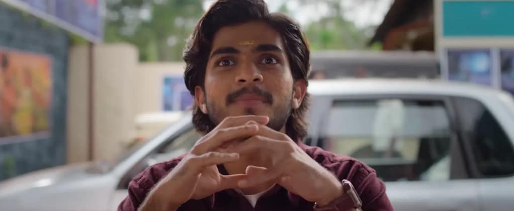 Naslen clasping his hands in excitement with a car in background in Mollywood Times. Image credit: Mollywood Times (2026) film still - via Sony Music Malayalam/YouTube.