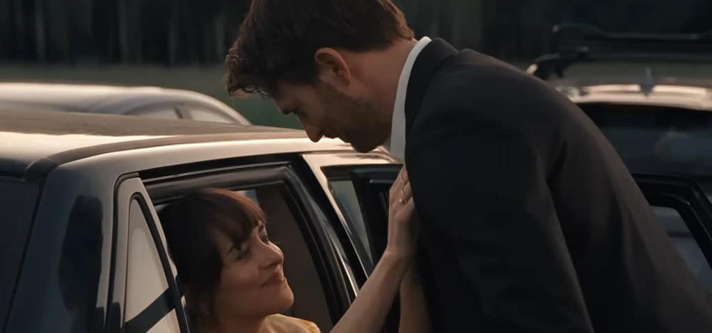 Dakota Johnson looking up from a car window at Chris Evans in a suit from the movie, Materialists (2025).