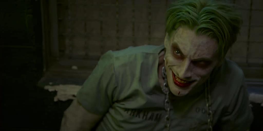 Aaron Schoenke as The Joker in an Arkham Asylum prison uniform with green hair and a sinister grin. Image credit: Batman: Dying Is Easy film still - via batinthesun/YouTube.