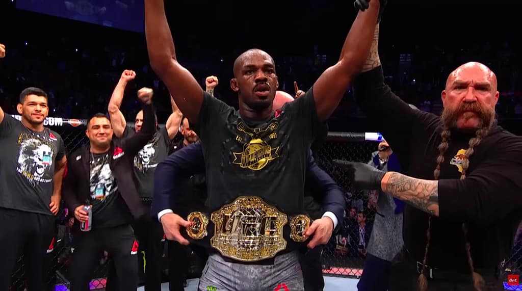 Jon Jones raises his arms in victory with the UFC Championship belt around his waist. Image credit: UFC/YouTube.