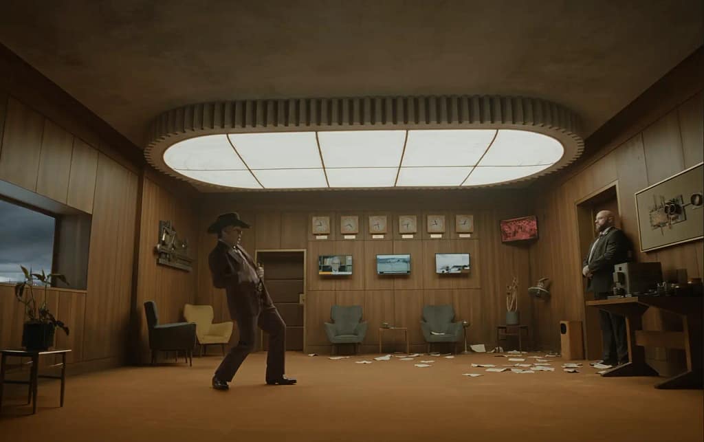 Tom Cruise wearing a cowboy hat and suit striking a theatrical pose inside a wood-paneled office. Image credit: Digger (2026) film still - via Warner Bros./IMAX/YouTube.