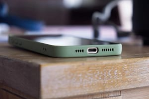 Close up shot of a modern smartphone in a green case resting on a wooden table